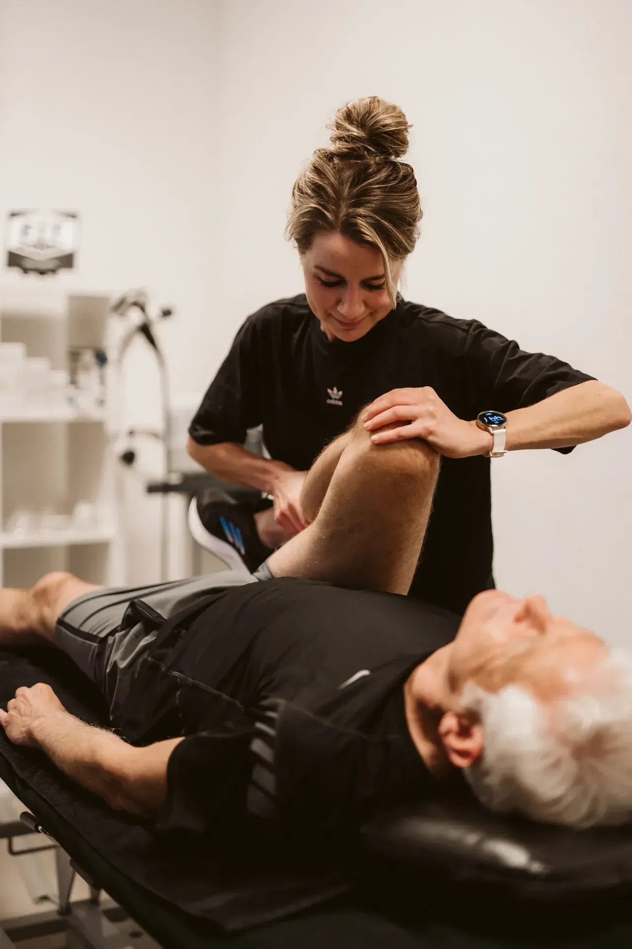 Fysiotherapeut onderzoekt de gebogen knie van een cliënt op de behandelbank