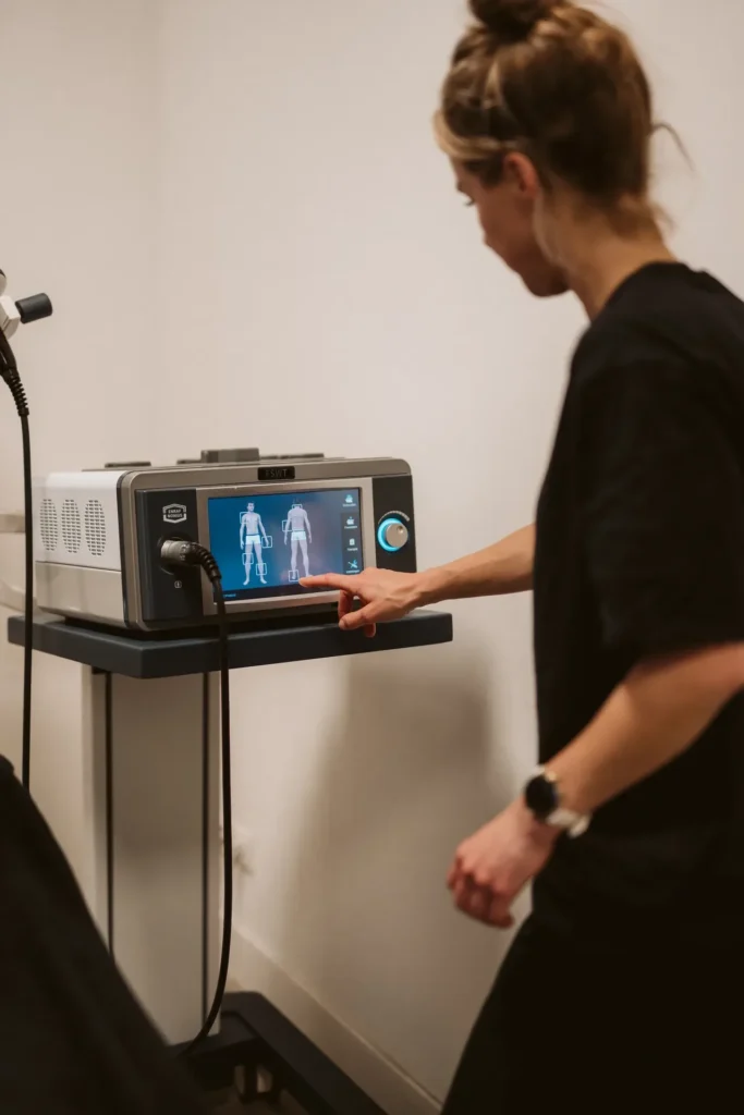 Fysiotherapeut stelt het shockwave-apparaat in via het touchscreen