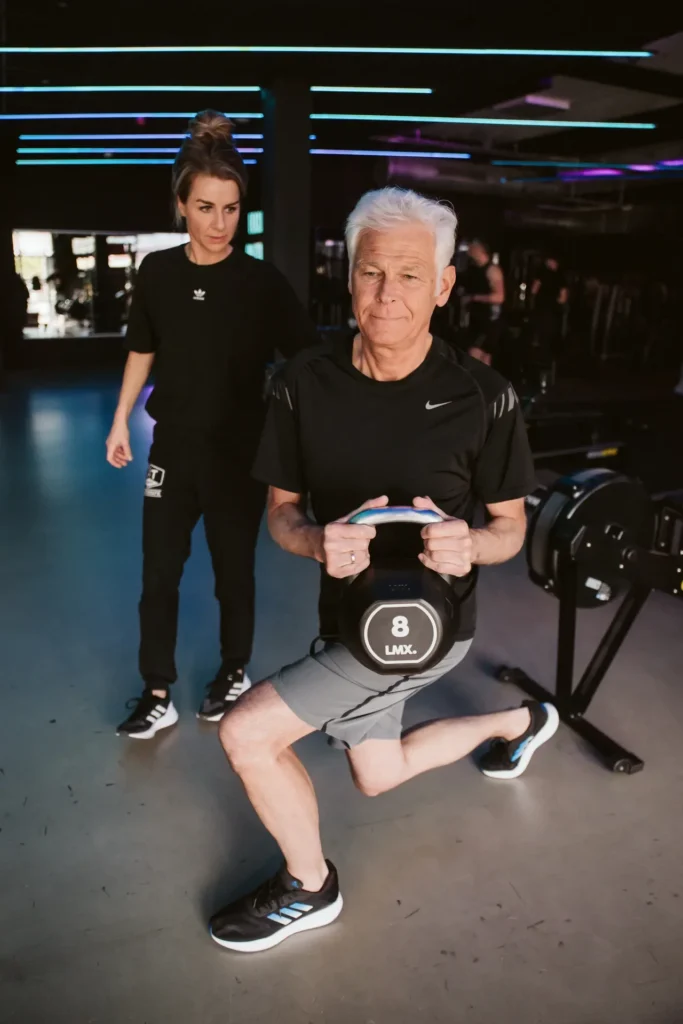 Lunge-oefening met kettlebell onder begeleiding van de fysiotherapeut