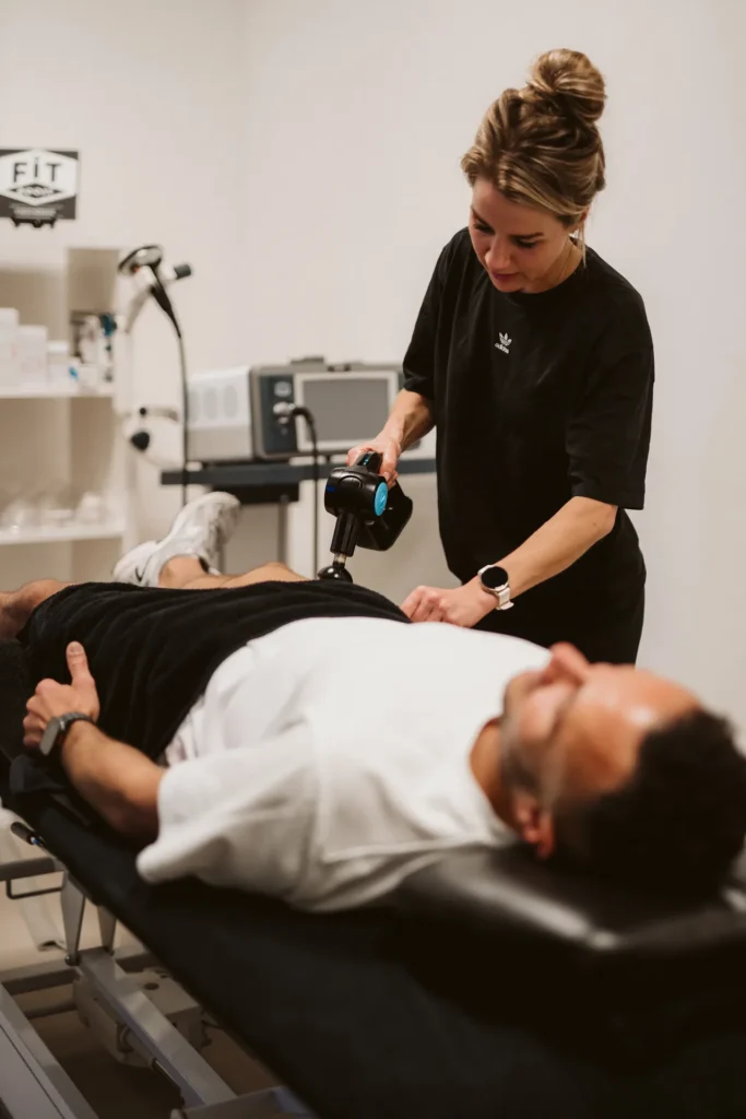 Behandeling met de massagegun op de behandelbank