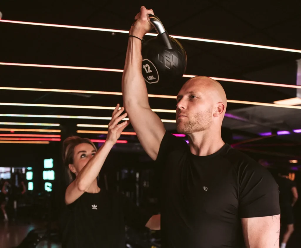 Schoudertraining met een kettlebell boven het hoofd onder begeleiding
