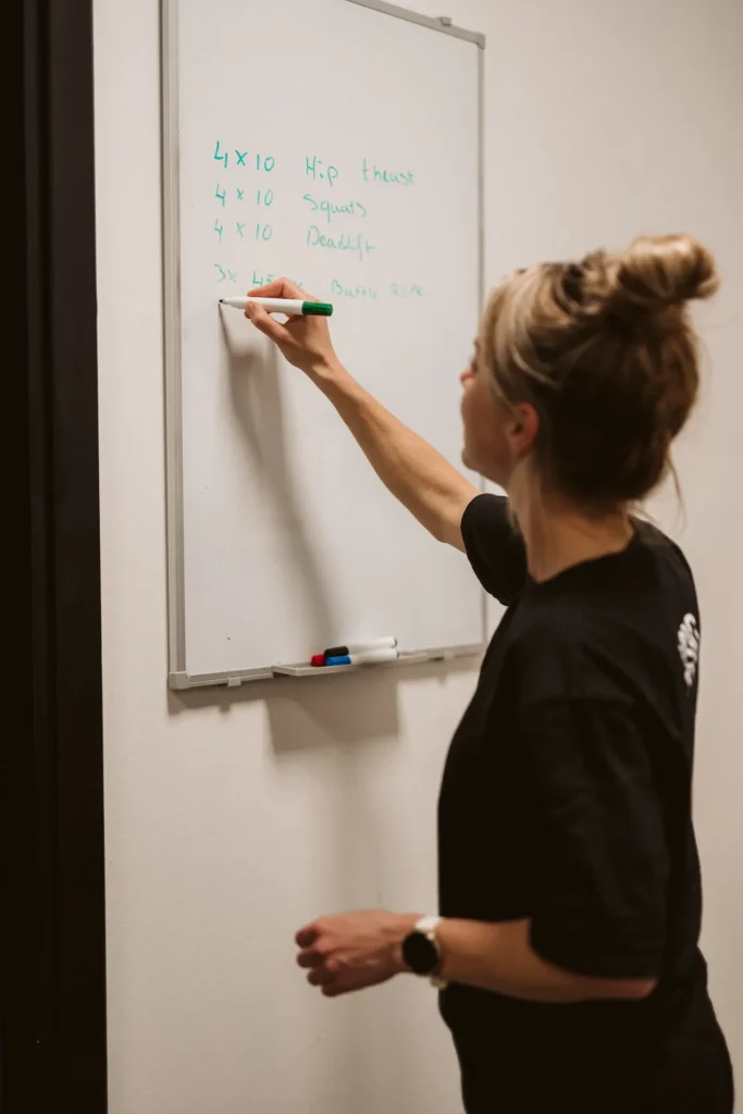 Fysiotherapeut schrijft een trainingsschema op het whiteboard